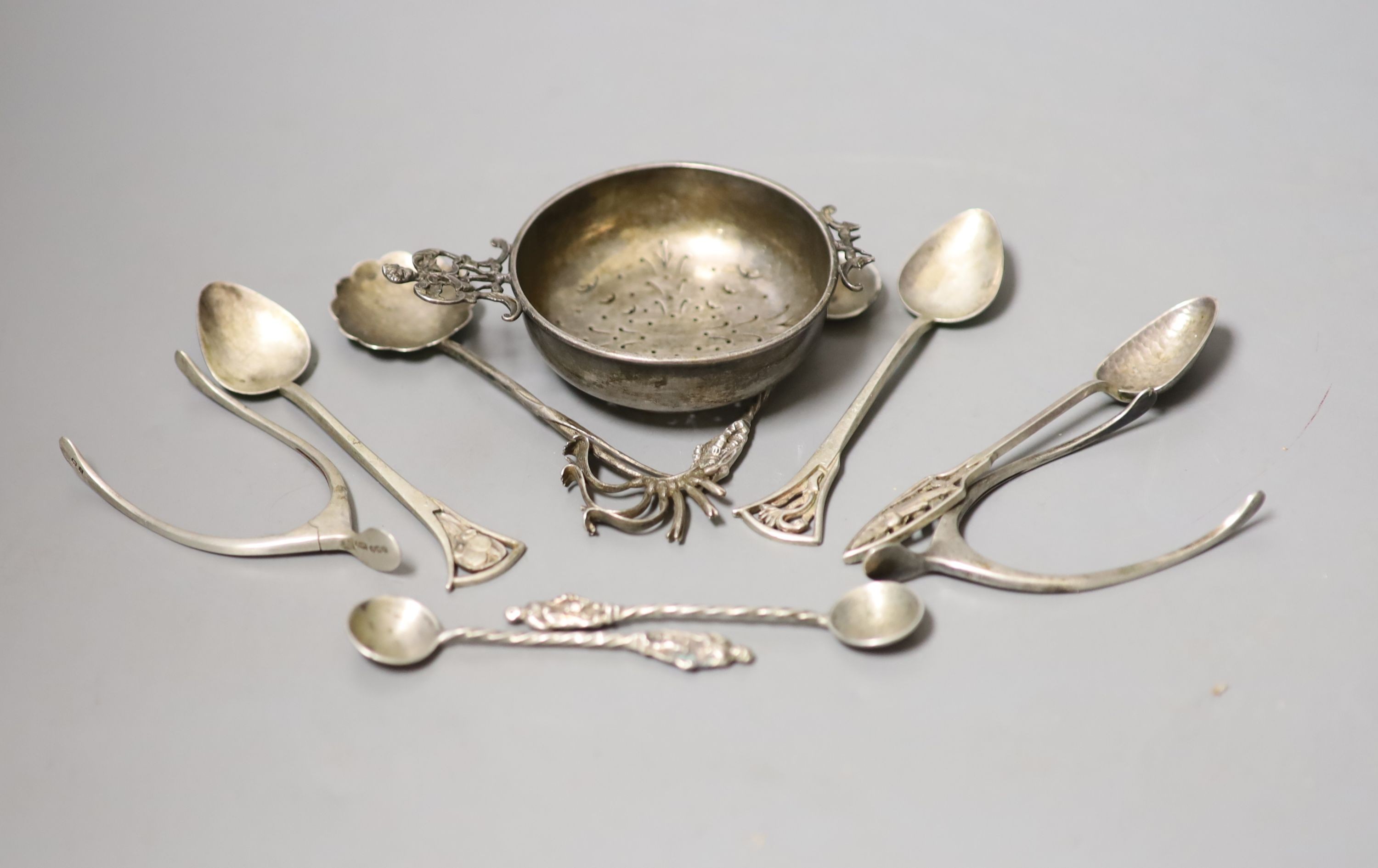 Small silver including two pairs of silver wishbone sugar nips, Levi & Salaman, Birmingham, 1922, a silver tea strainer and assorted spoons.